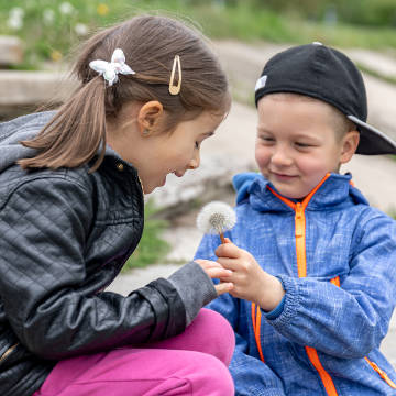 Zwei Kinder mit einer Pusteblume